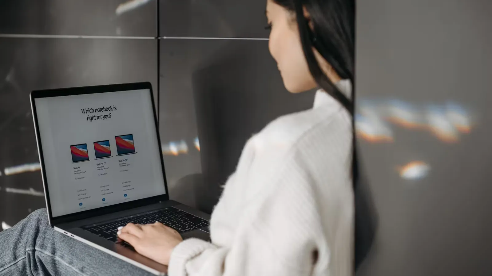 Woman sitting indoors using a laptop. Casual, modern tech vibe.